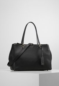 Svart läderhandväska med texturerad yta, dubbla handtag upptill och avtagbar axelrem. Utrustad med guldfärgad hårdvara och en etikett som accent.