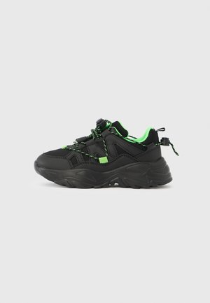Black and green sneakers with textured mesh and synthetic materials, featuring a chunky sole, elastic laces, and pull tab at the back.