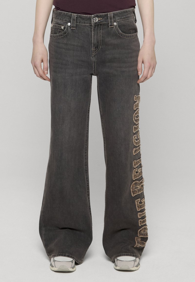 Pantalones vaqueros negros de pierna ancha con un adorno de logo desgastado en el lado izquierdo, con un diseño clásico de cinco bolsillos y herrajes metálicos.