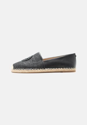 Svart slip-on espadrille-sko med vevd front, lærbakside, sydd jutesåle og en rund svart emblemer på toppen.