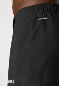 Schwarze Shorts aus leichtem Material mit elastischem Bund und dem Aufdruck "CLIMAPROOF" an der Seite.