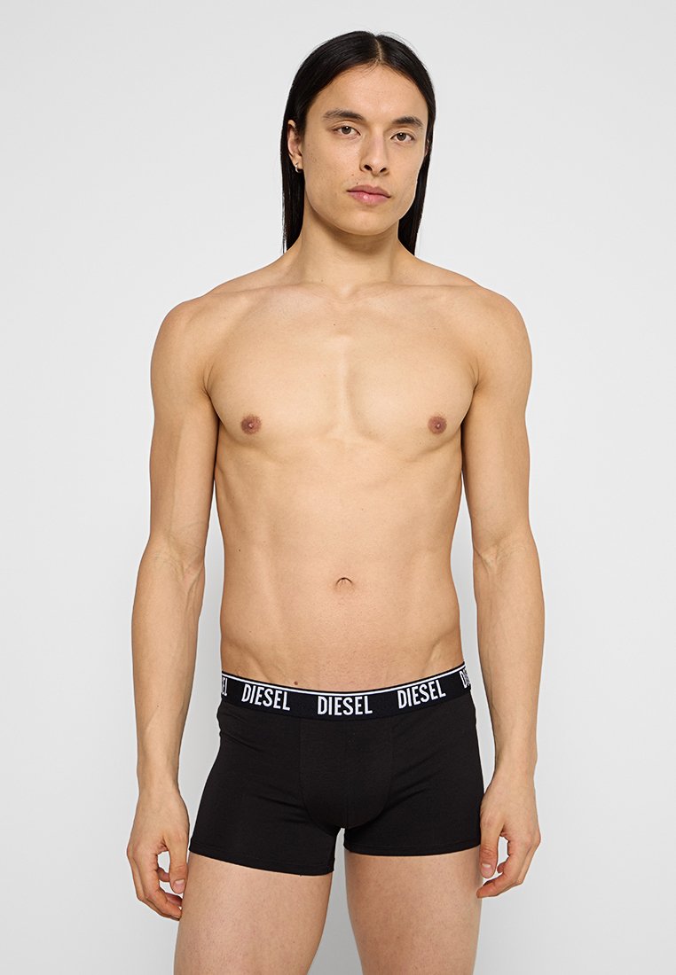 Boxers noirs en coton avec une ceinture logo "DIESEL" contrastante en blanc, design ajusté avec une texture lisse. Modèle posé en position verticale.