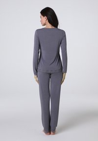 Completo pigiama grigio a due pezzi, composto da una maglia a maniche lunghe con un accento in pizzo all'orlo e pantaloni abbinati con bordo in pizzo ai polsini.