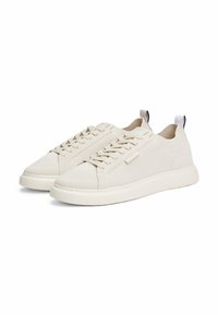 Zapatillas de malla beige claro con un acabado texturizado, punta redonda, cierre de cordones en la parte delantera y una lengüeta de contraste en el talón. Suela blanda.
