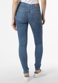 Smal blå jeans med hög midja, två bakfickor med en böjd söm, och en märkeslapp i läder bak.