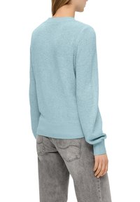 Hellblaue Strickjacke mit Rundhalsausschnitt, gerippten Bündchen und Saum. Verfügt über lange Ärmel und eine lockere Passform. Tragen mit grauen Jeans.