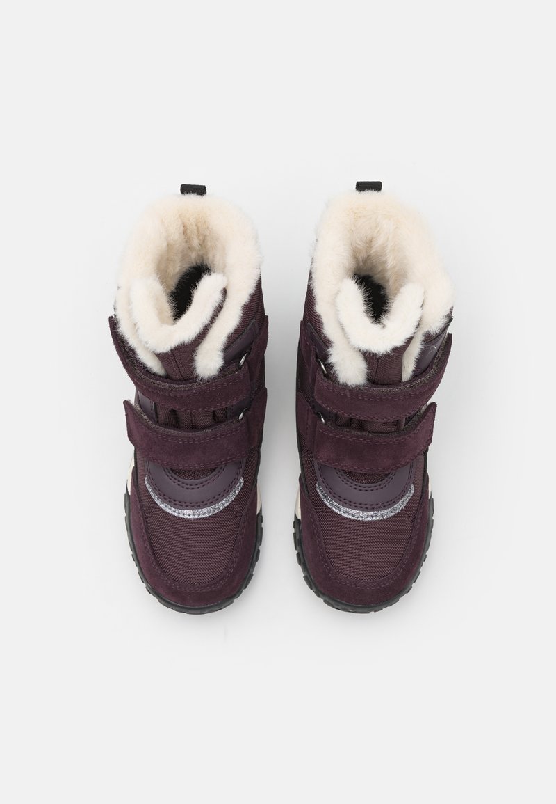 Lila Winterstiefel mit zwei Klettverschlüssen, weichem weißen Fellfutter, Gummisohle und silbernen Akzentdetails an den Seiten.