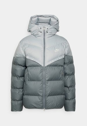 Hallgray puffertakiga, millel on kapuuts, heledama halli ülemise osaga, lukuga kinnitamine ja küljetaskud. Rinnal Nike'i logo.