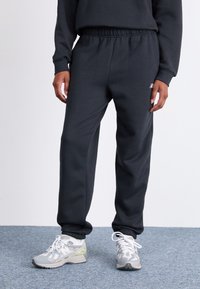 Mørkegrå sweatpants med elastisk talje og manchetter, lavet af blødt materiale; har et lille logo på forsiden.