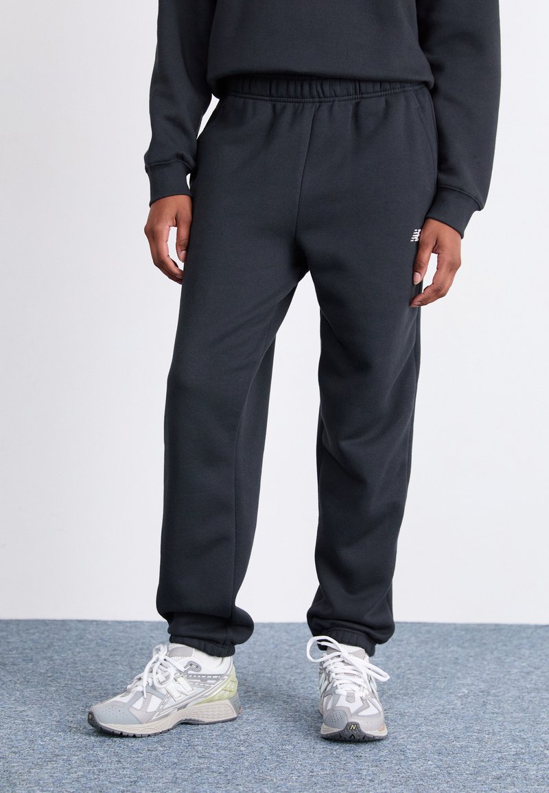 Mørkegrå sweatpants med elastisk talje og manchetter, lavet af blødt materiale; har et lille logo på forsiden.