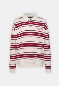 Polo z długim rękawem w kolorze kremowym w paski czerwone i czarne. Posiada zapinany kołnierzyk oraz wyszywane logo "HILFIGER NEW YORK" na piersi.