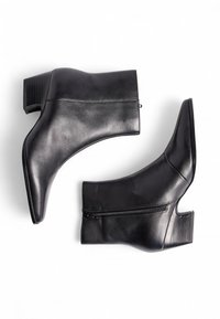 Mustat nahkaiset nilkkapituiset saappaat, joissa on teräväkärkinen muotoilu, kulmikkaat linjat ja tukevat korot. Varustettu sivuvetoketjulla helppoa pukemista varten.