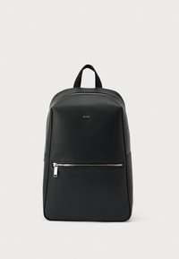 Mochila de cuero negro con textura suave, asa superior, correas ajustables para los hombros y un bolsillo delantero con cremallera. Diseño minimalista.