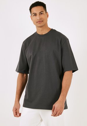 Mørkegrå oversized t-shirt, korte ærmer, rund halsudskæring, lavet af bomuld med en glat overflade og minimale sømme.