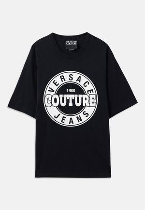 Crna pamučna majica s velikim bijelim kružnim logotipom sa tekstom "VERSACE COUTURE 1988" i "JEANS" u podebljanom tipu slova. Kratki rukavi.