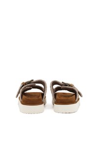 Bruna mockaskinnsandaler med vita gummisulor, med flätade remmar och en enkel spänndetalj. Bakifrån syns det vadderade fotbädden och remdesignen.