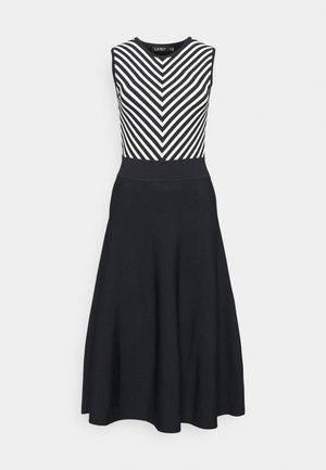 Ärmelloses schwarzes Kleid mit tailliertem Oberteil, das schwarz-weiße Chevronstreifen zeigt, und einem einfarbigen schwarzen ausgestellten Rock.