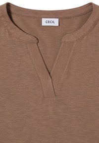 Haut brun à manches courtes en tissu doux et texturé. Présente un col en V et une étiquette de marque indiquant "CECIL".