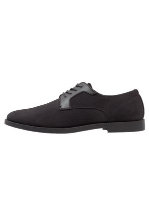 Chaussure formelle noire pour homme à lacets, finition mate et lisse, talon bas et bout arrondi, montrée de profil sur fond blanc.