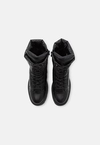 Bottines noires à la cheville avec une tige en cuir lisse, un col rembourré texturé, un laçage à l'avant et une semelle en caoutchouc robuste.