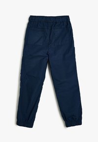 Marineblauwe cargo broek met elastische taille en twee achterzakken, en elastische boorden. Gemaakt van een lichtgewicht stof met een gladde textuur.