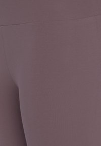 Paarse leggings met een soepele, rekbare textuur en hoge tailleband. De stof lijkt lichtgewicht en naadloos ontworpen te zijn.