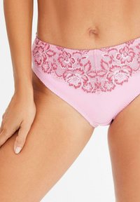 Bikini rosa in pizzo con una fantasia floreale in vita. Tessuto liscio su tutta la superficie, caratterizzato da un design a gamba alta e dettagli di cucitura sottili.