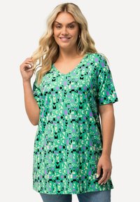 Vihreä tunika, jossa on löysä malli, V-pääntie, lyhyet hihat ja geometrinen kuvio mustassa, vaaleanpunaisessa ja valkoisessa. Valmistettu pehmeästä kankaasta.