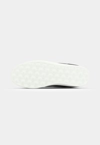 Zwarte sneakersole met een witte buitenzool, voorzien van een gestructureerd grippatroon en reliëf logo-details overal.