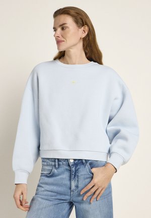 Light blue sweatshirt made of textured fabric, featuring dropped shoulders, a cropped fit, and an embroidered yellow sun design on the chest.