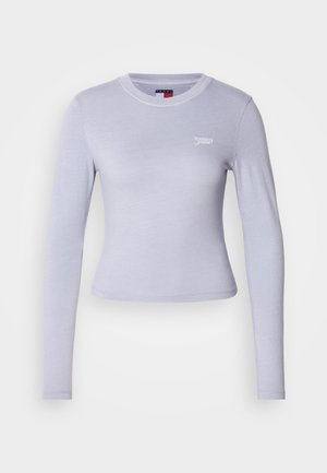 Camiseta de manga larga en un suave color lavanda, hecha de tejido blando, con un escote redondo, corte ajustado y un pequeño logo blanco en el pecho.