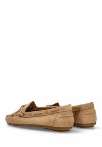 Mocasines de ante en tono marrón claro con una textura suave, forma redondeada, costuras prominentes y ojales metálicos para un diseño de cordones. Suelas de goma para mayor tracción.