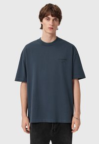 Dark gray, oversized cotton t-shirt with short sleeves, crew neckline, and a small black logo print on the left chest.