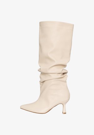 Kremowe, skórzane, luźne kozaki za kolano z wąskim noskiem i smukłym, średniej wysokości obcasem.