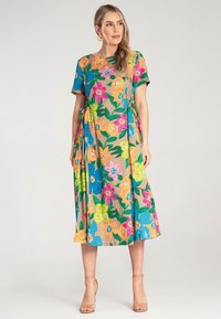 Blumenkleid im Maxistil aus weichem Stoff, mit einer Vielzahl von leuchtend bunten Blumen auf einem beigen Hintergrund, kurzen Ärmeln und einer lockeren Passform.