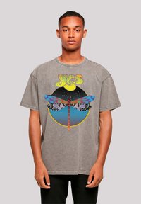 Gray oversized T-shirt with a round graphic featuring a colorful dragonfly against a cosmic background and bold text above. Short sleeves.