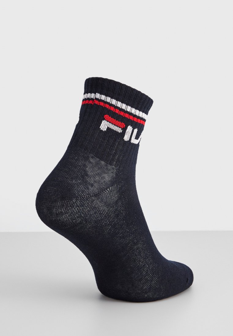 Jedna czarna skarpetka do kostek z białymi i czerwonymi paskami u góry oraz częściowo widocznym logo marki na jednolitym tle.