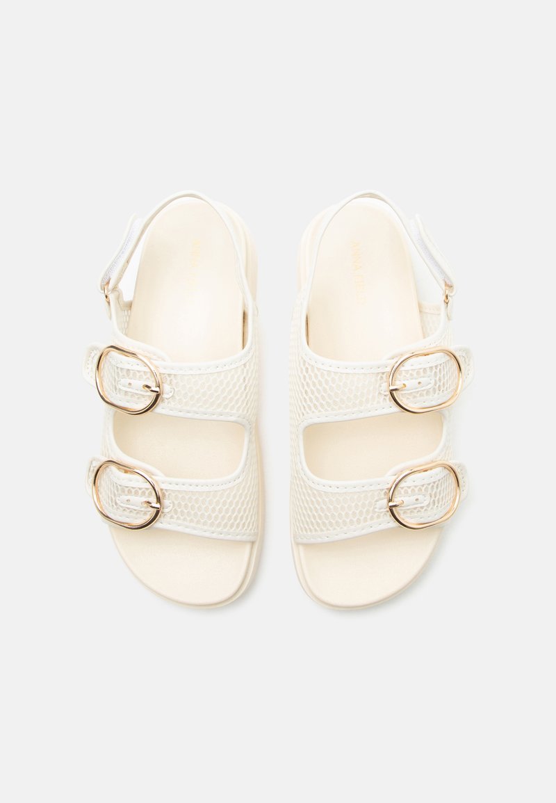 Sandalias blancas con dos correas de malla y hebillas en tono dorado, con puntera abierta y tira trasera, exhibidas sobre un fondo claro y simple.
