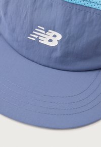 Cappellino leggero blu con visiera curva, dotato di un pannello superiore traspirante in una tonalità più chiara, e un logo New Balance bianco sul davanti.
