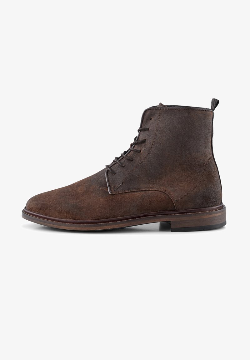 Brown suede ankle boot with a rounded toe, lace-up design, and contrasting brown sole. Features a small loop at the top for easy wear.