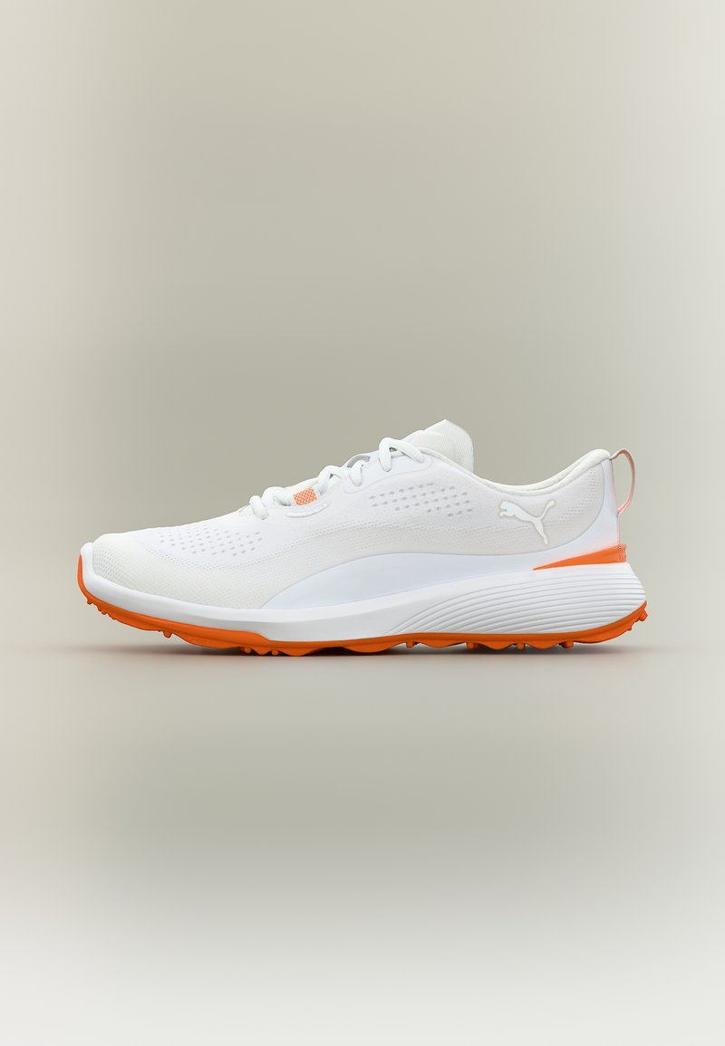 Λευκό αθλητικό παπούτσι με πορτοκαλί σόλα και λεπτομέρειες, σχέδιο με κορδόνια και λογότυπο Puma στο πλάι, πάνω σε ουδέτερο φόντο.
