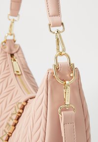 Ροζ επενδυμένη δερμάτινη τσάντα με χρυσές λεπτομέρειες και αποσπώμενο λουρί. Διαθέτει κλείσιμο με φερμουάρ και υφή με γεωμετρικό σχέδιο.