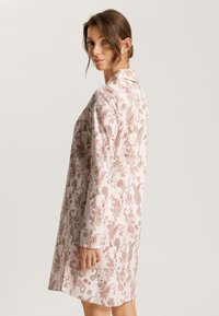 Vestido rosa con estampado de paisley, con cuello, mangas largas y un corte relajado. La tela parece suave y ligera, con un detalle intrincado.