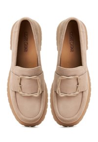 Beige mokkasiner i alen med en kraftig lys brun såle og en dekorativ firkantet spenne på reimen. Glatt tekstur og minimalistisk design.