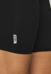 Černé sportovní šortky z hladkého, pružného materiálu s bílou logo štítkem "B DRY", mají přiléhavý střih.