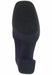 Fialová semišová podrážka s texturovaným černým gumovým dnem. Disponuje nízkým podpatkem a vyraženým logem na boku. Ploché dno pro stabilitu.