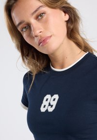 Navy blue cotton t-shirt with a round neck, white trim, and a white number "89" printed on the front. Short sleeves.