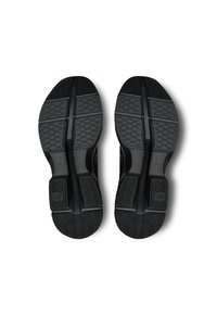 Black athletic shoe soles with textured rubber, featuring linear and diamond patterns for grip. Minimal branding and structured design.