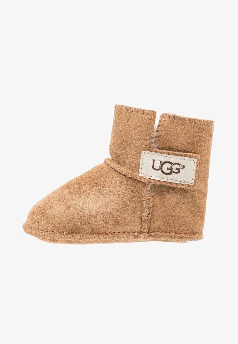 Brun mocka stövel med mjuk textur, rund tå och kardborreband. Har en liten UGG-logotyp på sidan. Ungefärlig höjd: ankeln.