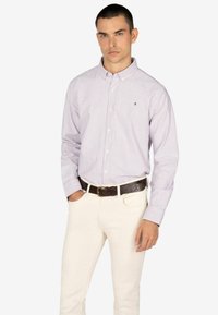 Lichtpaarse en witte gestreepte button-up shirt, gemaakt van katoen, lange mouwen, kraag, gedragen met witte broek en een donkere riem.